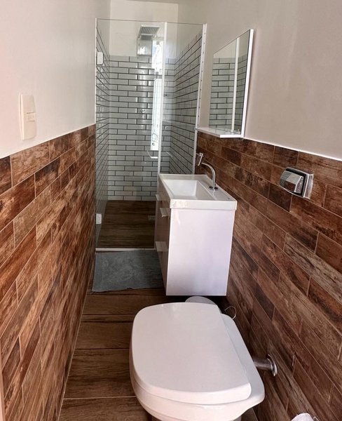 Banheiro de suíte com box e revestimento amadeirado