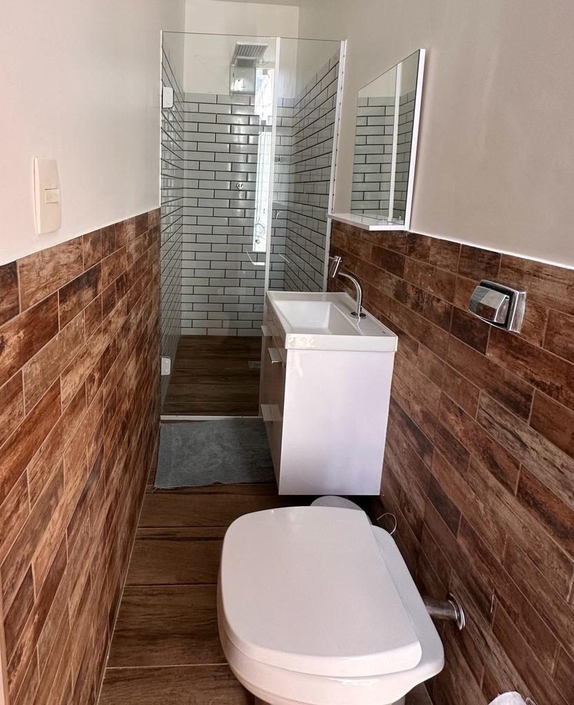 Banheiro de suíte com box e revestimento amadeirado