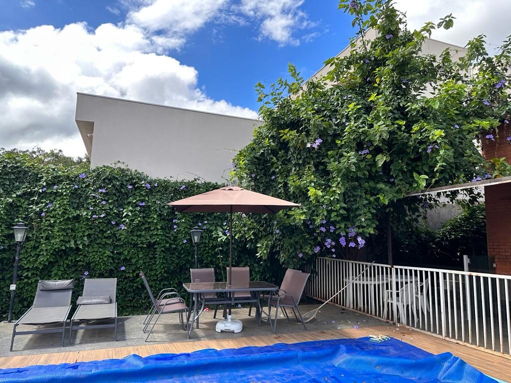 Deck da piscina com guarda-sol e espreguiçadeiras