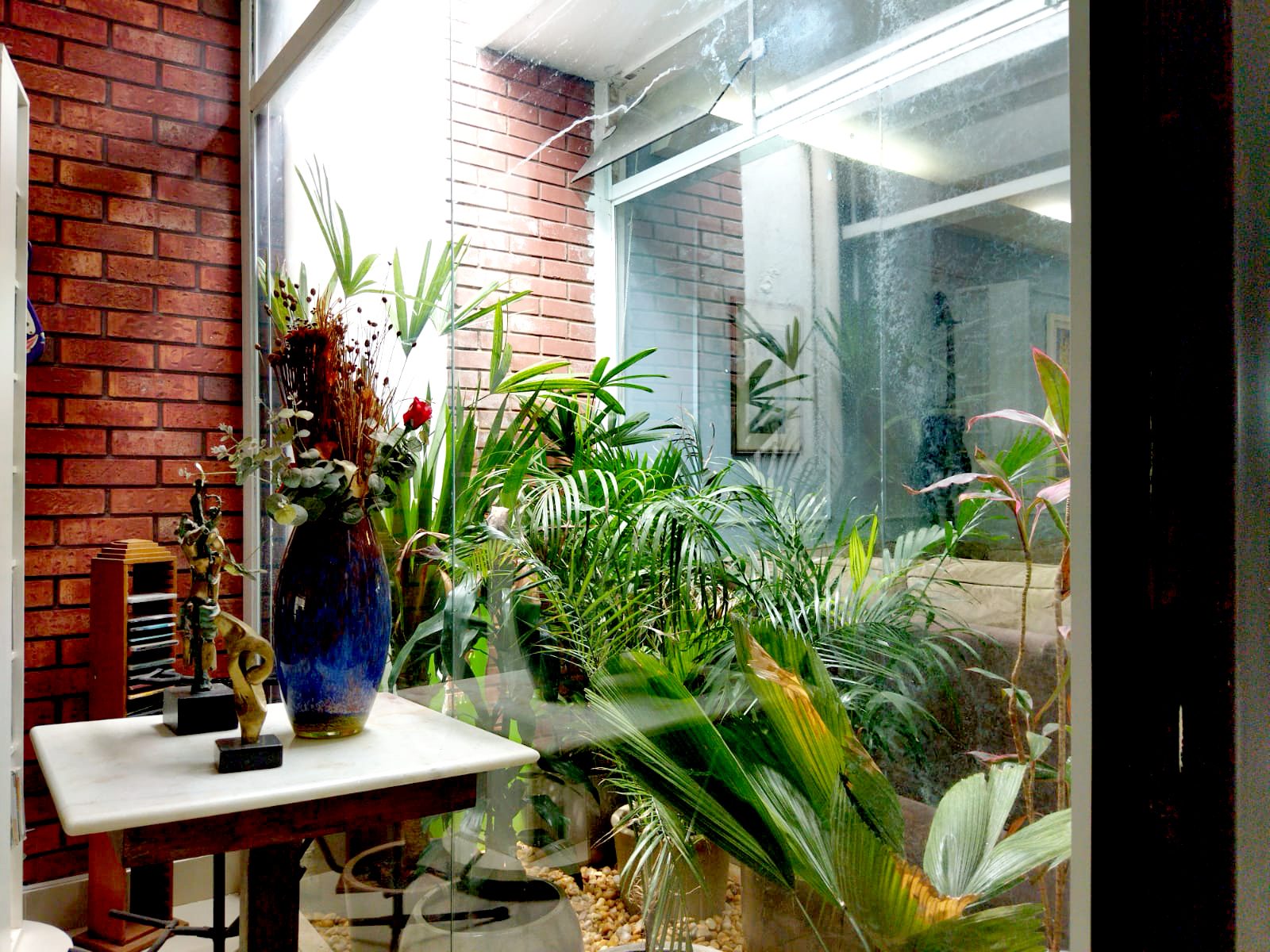 Jardim de inverno com plantas e parede de tijolo aparente