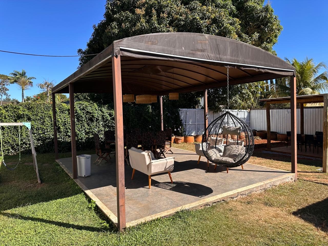 Pergolado com poltronas e balanço suspenso no jardim