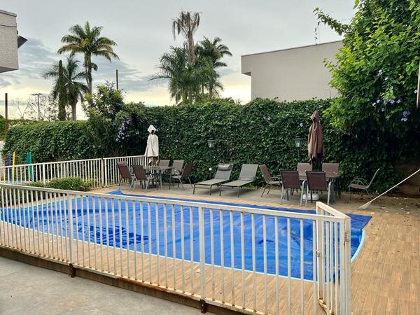 Piscina, deck e jardim com cerca viva florida