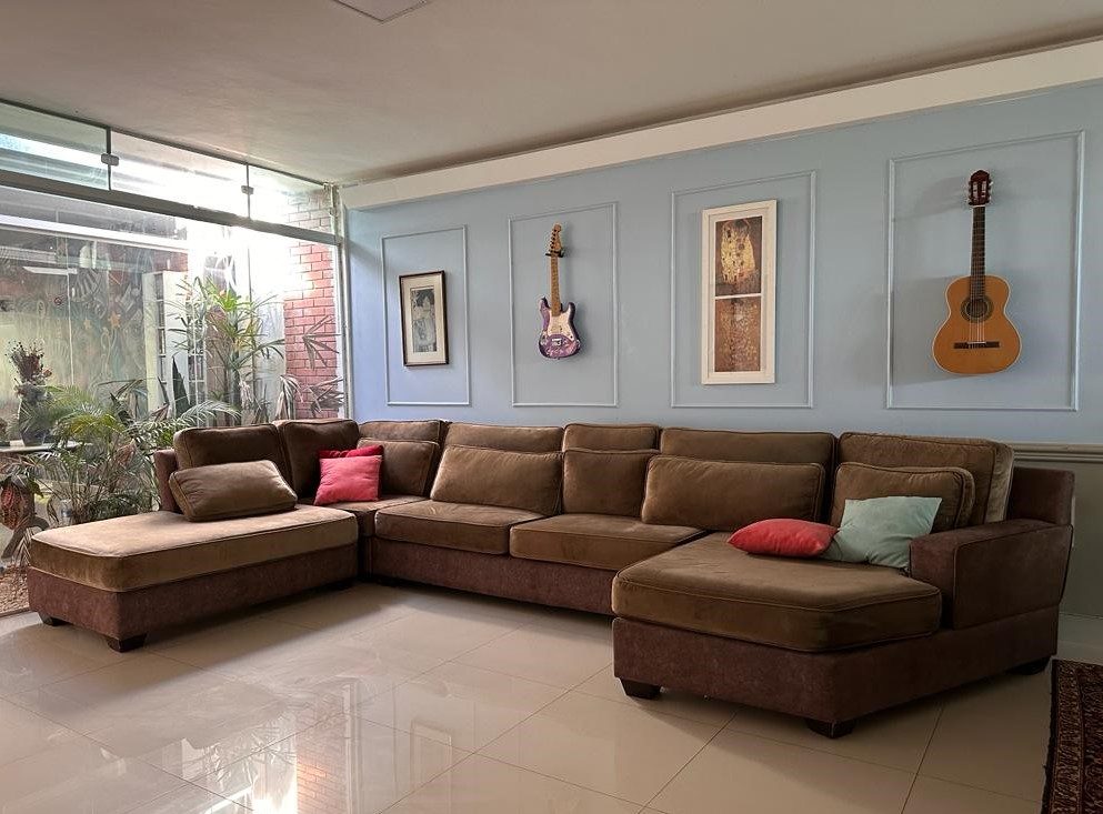Sala de estar com sofá em L e instrumentos na parede