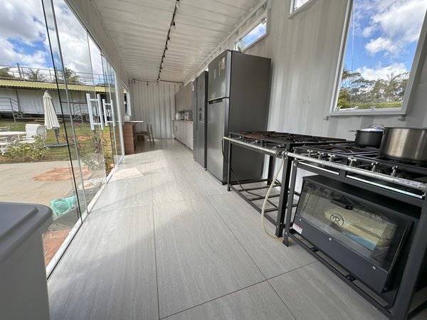 Cozinha em linha com fogões profissionais e janelas para a área externa