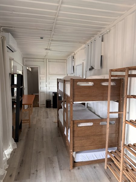 Quarto com beliches de madeira, cozinha compacta e área de estar