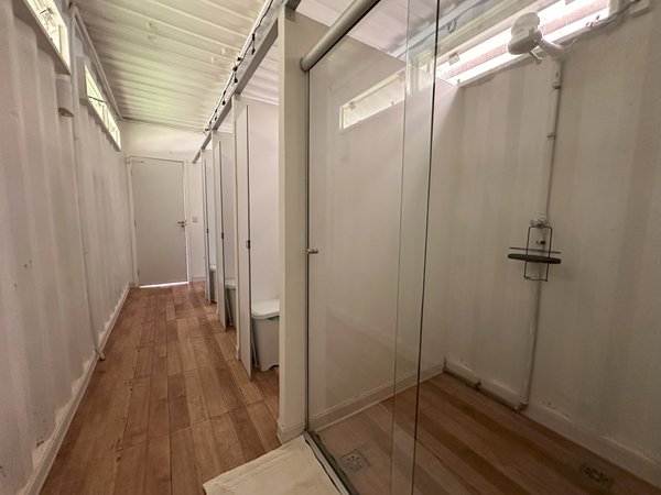 Banheiro com box de vidro e piso de madeira