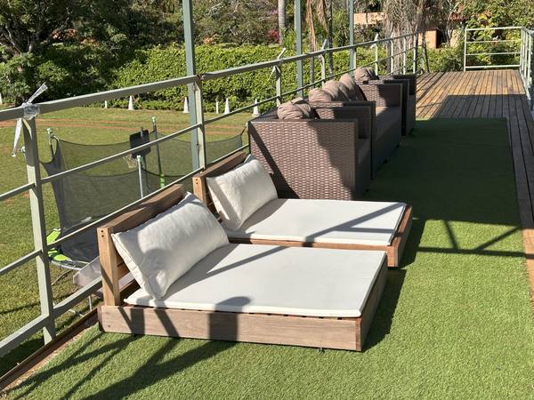 Espreguiçadeira dupla no deck de grama sintética, de frente para o jardim