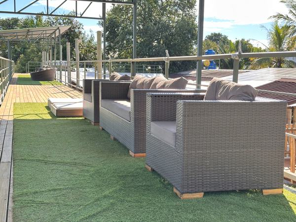Lounge do deck superior com sofás de vime sobre grama sintética