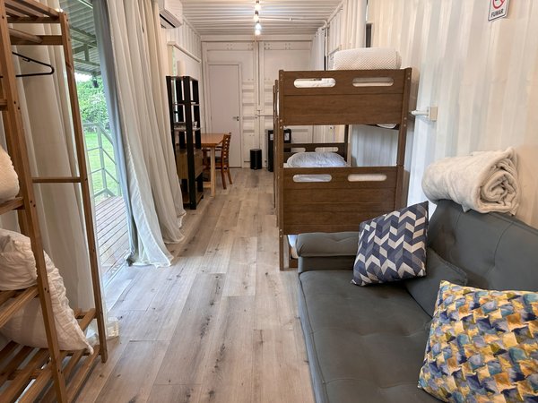 Quarto com beliche, sofá e arara de apoio