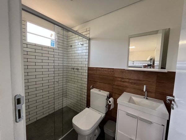 Banheiro com box de vidro, bancada e espelho