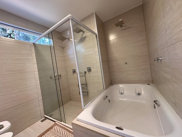 Banheiro com banheira de hidromassagem e box de vidro