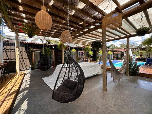 Cadeira-ovo suspensa e rede junto à piscina, sob o pergolado