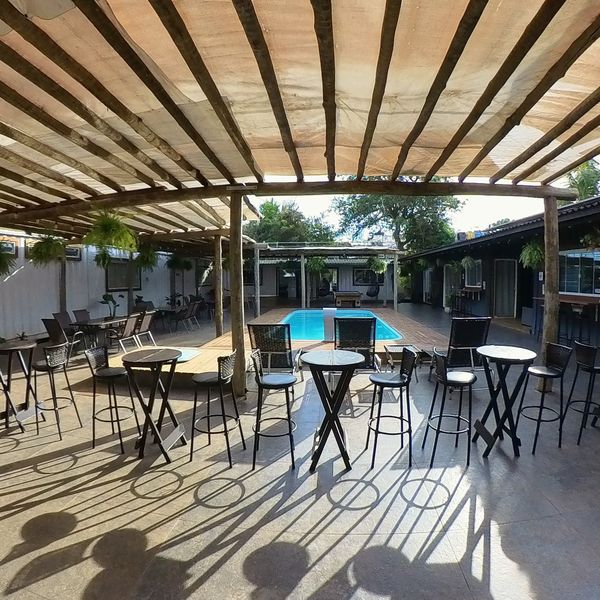 Mesas altas y taburetes junto a la piscina