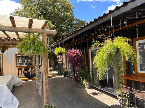 Pergolado com samambaias e flores penduradas ao longo da varanda