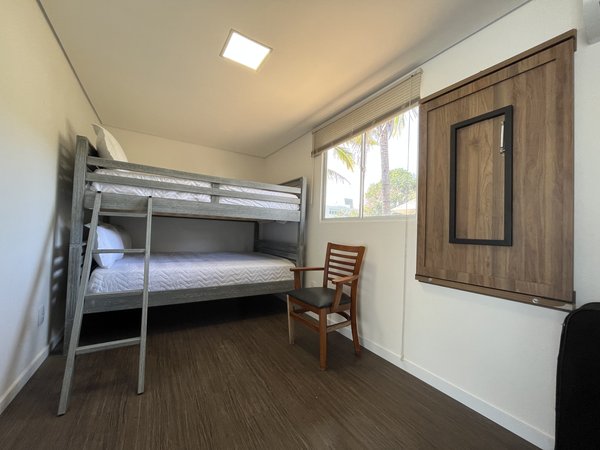 Quarto com beliche, cadeira e luz natural