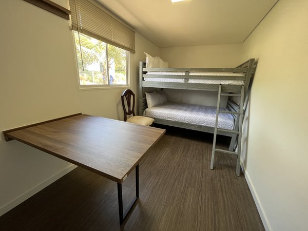Quarto com mesa de trabalho ao lado do beliche