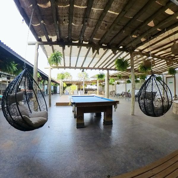 Mesa de billar y sillas colgantes en el patio cubierto