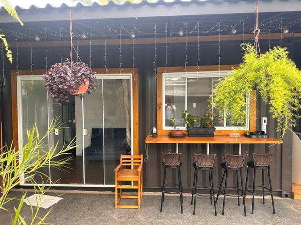 Varanda com bancada de bar, banquetas altas e plantas suspensas